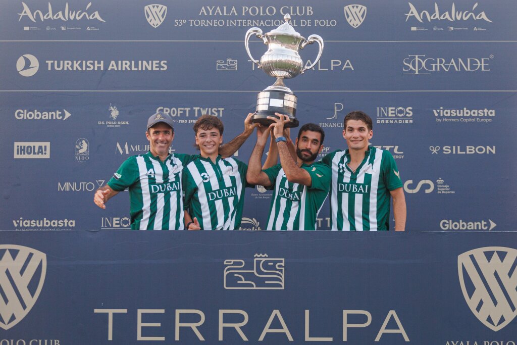 A team of polo players in green and white striped shirts celebrates with their trophy won in Dubai, showcasing teamwork and victory.