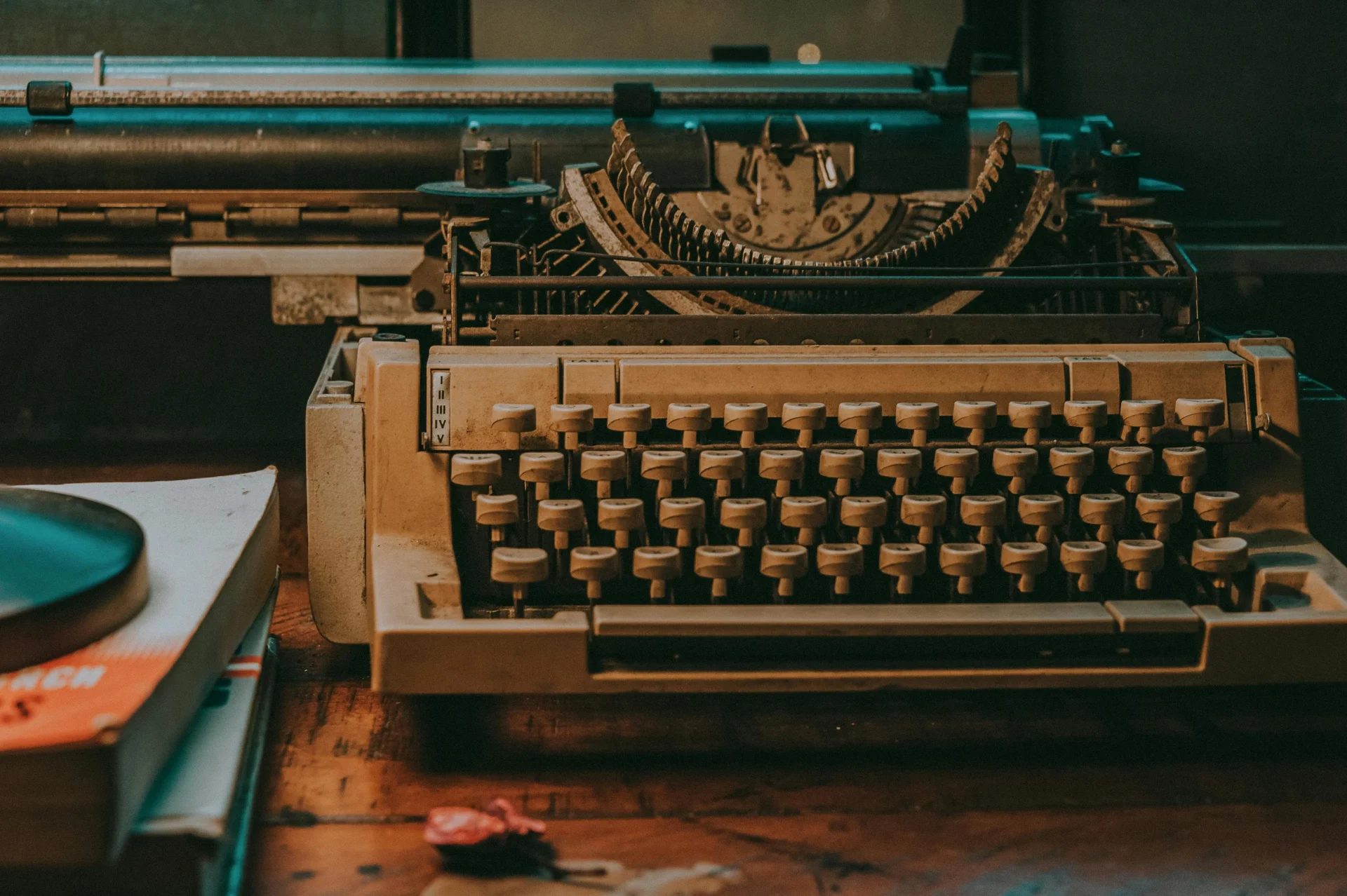 An old typewriter positioned on a desk next to a book, symbolizing a connection to classic writing and literature