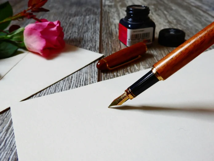 A classic fountain pen lies next to a sheet of paper featuring a beautifully illustrated rose, representing artistry and romance